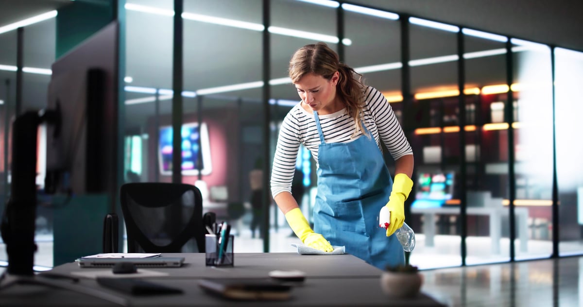 Professional cleaner detailing an office desk after construction