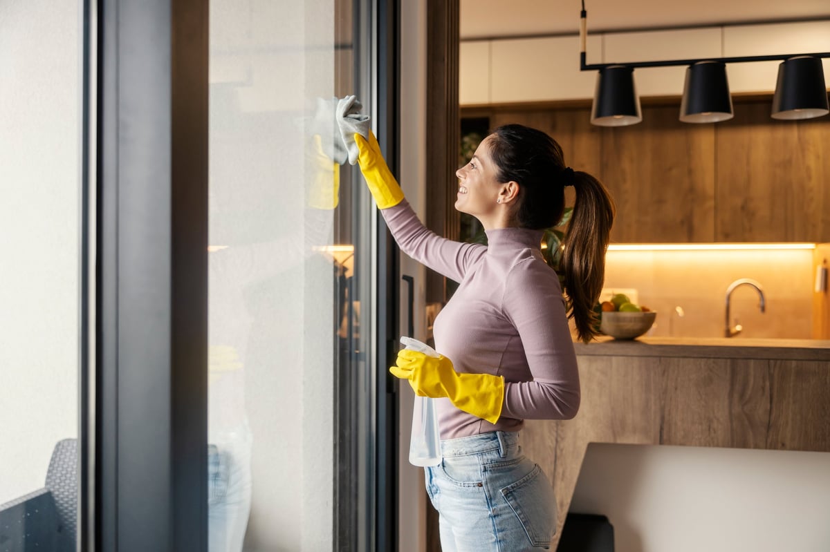 A professional cleaner wiping windows in a bright, freshly cleaned home