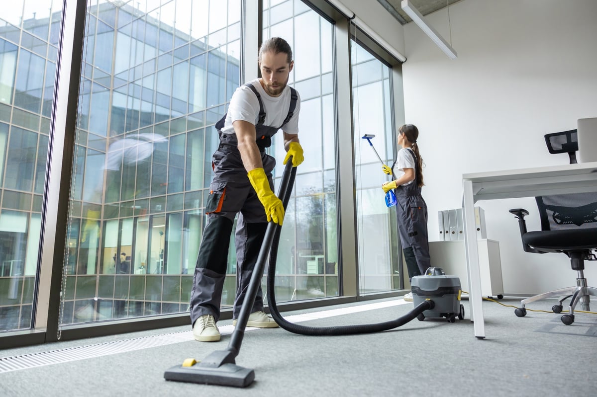 Uniformed cleaner vacuuming the floor of a room